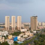 Aerial view of high rise towers nearby buildings road and greenery